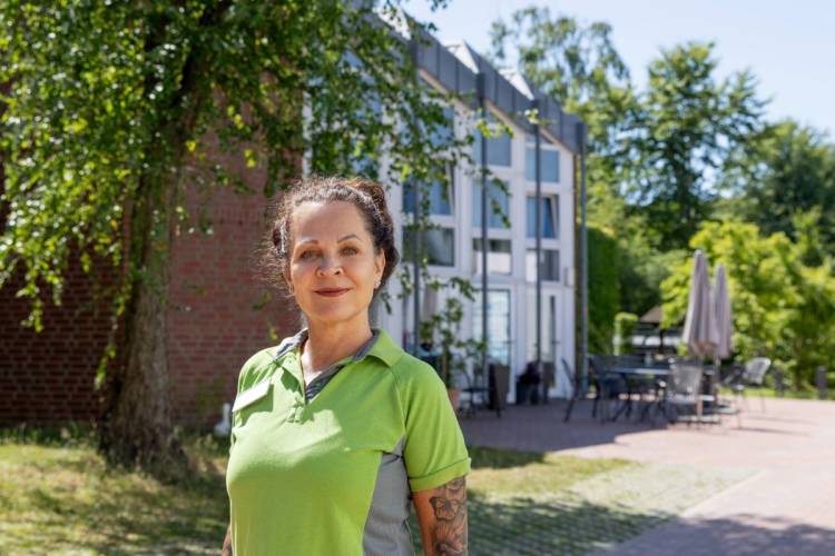 Pflegefachkraft Sabine Piric vor der Terrasse des Standorts Öjendorf von PFLEGEN & WOHNEN HAMBURG.