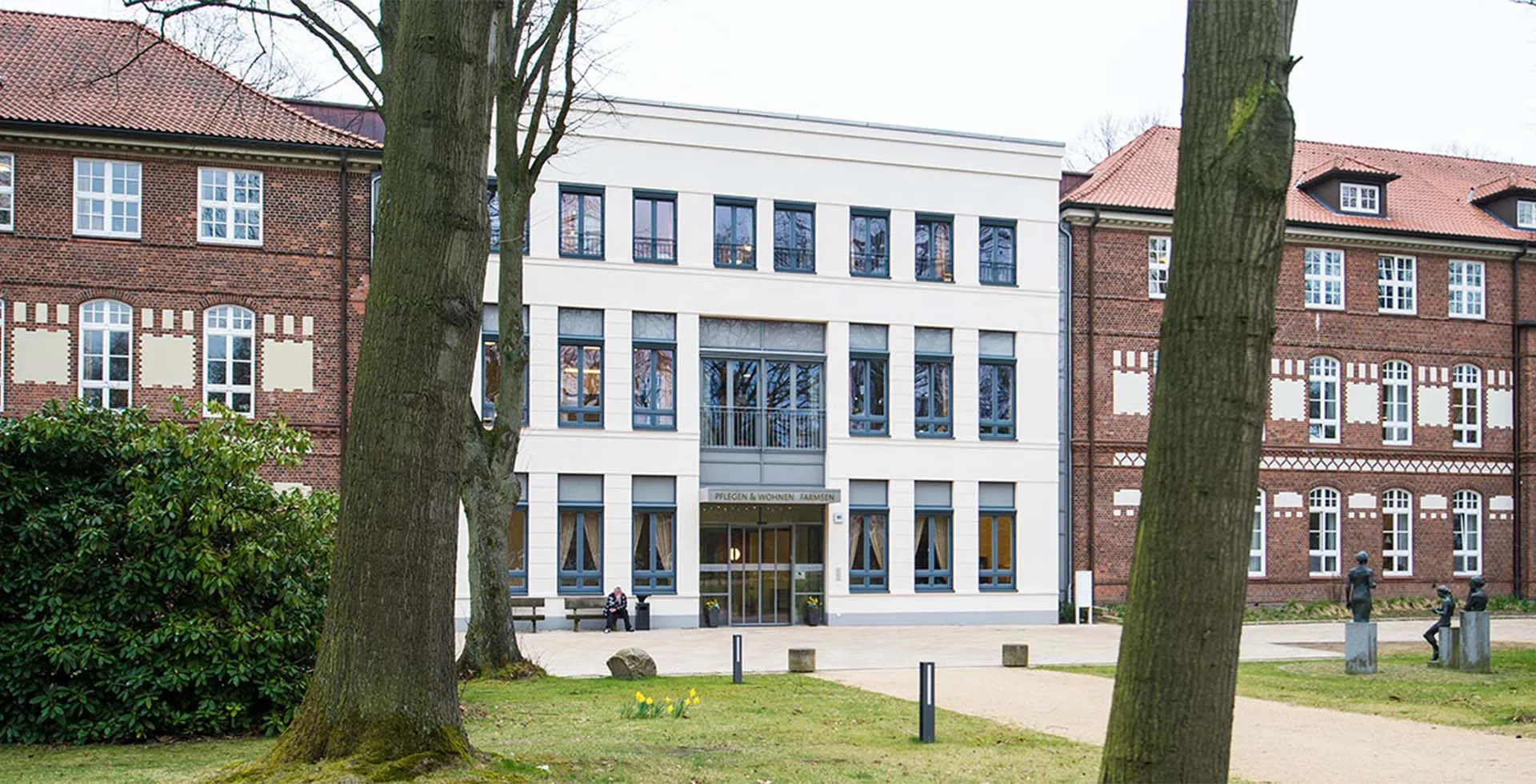Das moderne Pflegezentrum PFLEGEN & WOHNEN HAMBURG Farmsen mit Springbrunnen, gepflegter Parkanlage und Fokus auf Betreuung.