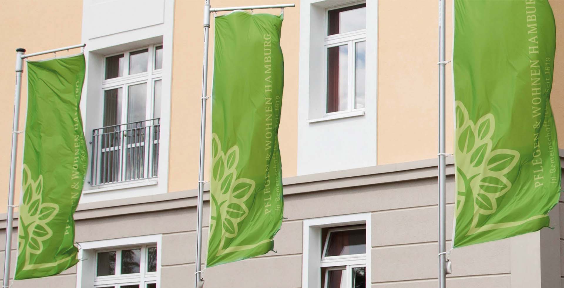 Fahnen von PFLEGEN & WOHNEN HAMBURG vor dem Hauptgebäude der Verwaltung.